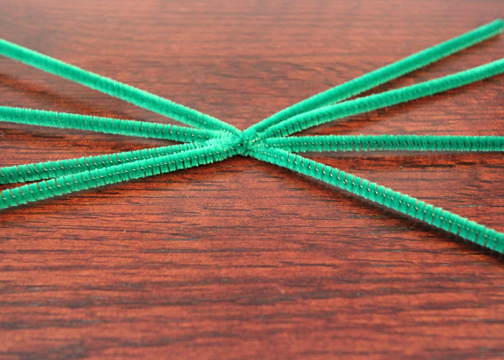 Four pipe cleaners twisted together to create spider legs for pine cone craft